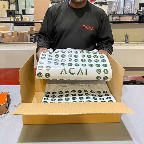 Duo Packaging employee holding ACAI Outdoorwear Branded Mailing Bags manufactured at Manchester HQ.